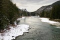 Pacific Northwest river flowing between snow covered beaches in winter Royalty Free Stock Photo