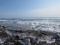 Pacific Ocean, waves and views of the snow-covered hill in winter in sunny weather in Kamchatka, Russia Royalty Free Stock Photo