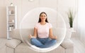 Pacified calm contented smiling millennial european woman meditating on sofa in living room interior Royalty Free Stock Photo