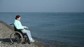 Pacified caucasian woman in a wheelchair on the seashore.