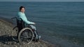 Pacified caucasian woman in a wheelchair on the seashore.