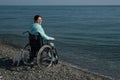 Pacified caucasian woman in a wheelchair on the seashore.