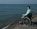 Pacified caucasian woman in a wheelchair on the seashore.