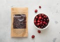 Pack of dried sweet cranberry and bowl of ripe cranberries on light background.Macro