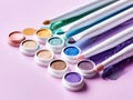 Pack of eyeshadows of various colors with sponge next to a light purple background