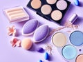 Pack of eyeshadows of various colors with sponge next to a light purple background