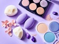 Pack of eyeshadows of various colors with sponge next to a light purple background