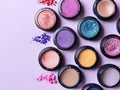 Pack of eyeshadows of various colors with sponge next to a light purple background