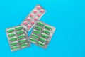 Pack of pills on a blue background. Copy space. Blisters of pink tablets and green capsules. Medicine concept. Royalty Free Stock Photo