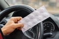 Pack of pills in the hands of the driver on a blurred background of the steering wheel in the car