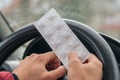 Pack of pills in the hands of the driver on a blurred background of the steering wheel in the car