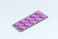 Pack of 10 pink oblong pills isolated on a white background