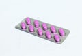 Pack of 10 pink oblong pills isolated on a white background