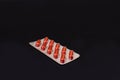 A pack of red capsule tablets on a black background Royalty Free Stock Photo