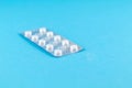 Pack of white pills packed in blister with copy space on blue background. Focus on foreground, soft bokeh Royalty Free Stock Photo