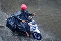 a package courier who rides a motorbike who drives through flood waters during heavy rain in a residential area