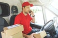 Package delivering - delivery man using mobile phone while sitting in van Royalty Free Stock Photo