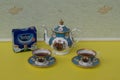 A package of original English Tetley`s teabags next to English teacups with saucers and teapot, fine bone china porcelain Royalty Free Stock Photo