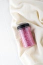 Package of pink shiny crystal salt on a bathroom beige towel. Jar of shimmering pink sea salt for home spa. Idea of relaxation,