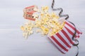 Package with scattered popcorn, two movie tickets and film, on a light gray background Royalty Free Stock Photo