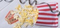 Package with scattered popcorn, two movie tickets and film, on a light gray background, close-up Royalty Free Stock Photo