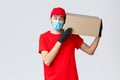 Packages and parcels delivery, covid-19 quarantine delivery, transfer orders. Curious courier in red uniform, gloves and Royalty Free Stock Photo