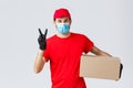 Packages and parcels delivery, covid-19 quarantine delivery, transfer orders. Friendly courier in red uniform, face mask Royalty Free Stock Photo