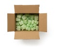 Packaging foam filler in the cardboard parcel box isolated on a white background. Open brown box filled with green loose fillers