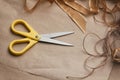 Packaging process. Presents wrapping. Yellow scissors, ribbons, hemp strings and threads, brown craft paper texture background. Royalty Free Stock Photo