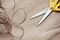 Packaging process. Presents wrapping. Yellow scissors, ribbons, hemp strings and threads, brown craft paper texture background. Royalty Free Stock Photo