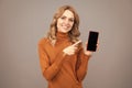 Happy girl pointing finger at mobile phone. Pointing index finger for advertising