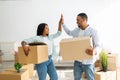 Packed and ready to move into new house. Black spouses giving high-five, holding cardboard boxes Royalty Free Stock Photo