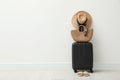 Packed suitcase, shoes and summer accessories near white wall indoors. Space for text