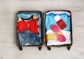 Packed suitcase with summer clothes and passport on wooden background