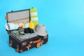 Packed vintage suitcase with clothes on blue background, space for text. Summer vacation