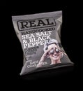 A Packet of REAL Handcooked Sea Salt and Pepper Flavour Potato Crisps on a black background.