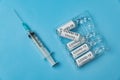 Packing of ampoules with vaccine COVID-19 and syringe on a blue background. Medical concept Royalty Free Stock Photo