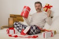 Packing Christmas presents ! young happy and attractive man sitting on bed cozy wrapping and preparing xmas gifts and boxes with Royalty Free Stock Photo