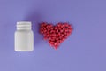 Packing pills. Heart shape made of pills. Pills spilling out of a jar on a purple background Royalty Free Stock Photo