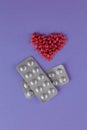 Packing pills. A scattering of red pills in the form of a heart on a purple background Royalty Free Stock Photo