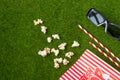 Packing with popcorn straws for soda on a green lawn with 3D glasses for watching a movie. Grass Watching films about nature. In