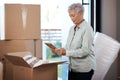 Packing up the past, preparing for the future. a senior woman looking at a photograph while packing boxes on moving day. Royalty Free Stock Photo