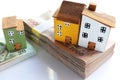 Packs of Thai baht banknotes, 1000 and 20 with wooden miniature houses on white background.