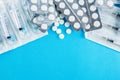 Packs of white pills and syringes on a blue background Royalty Free Stock Photo