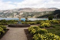 pacucha lake with mountains and a sculpture of a mermaid in a garden with flowers and trees
