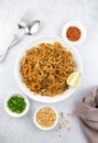 Pad thai with chicken, dried chili, peanuts, lime and green onions on a gray background, top view. Thai fried noodles. Royalty Free Stock Photo