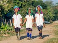 Three Padaung women in traditional dress walk along a village street.