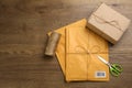 Padded envelopes, box, rope and scissors on wooden background, flat lay