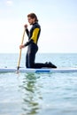 Paddle board sportsman standing paddling away on stand up paddleboarding at sea Royalty Free Stock Photo