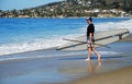 Paddle boarder entering water in Laguna Beach, California.